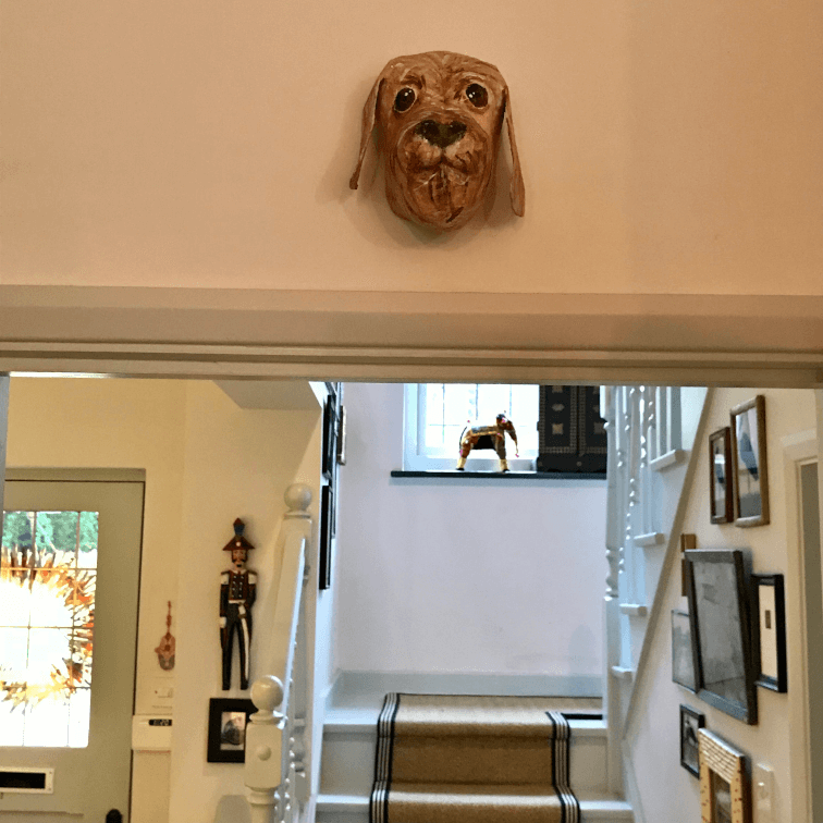 papiermache portret van een hond boven een deur