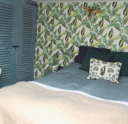 mooie papiermache giraf dierenkop op muur met palmbladerenbehang in slaapkamer